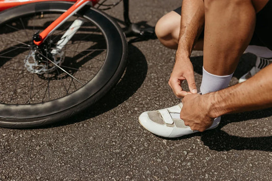 A cyclist laces up shoes next to a bike, ready for an outdoor journey.